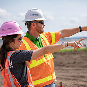 Employees in hardhats pointing to something that probably isn't even here